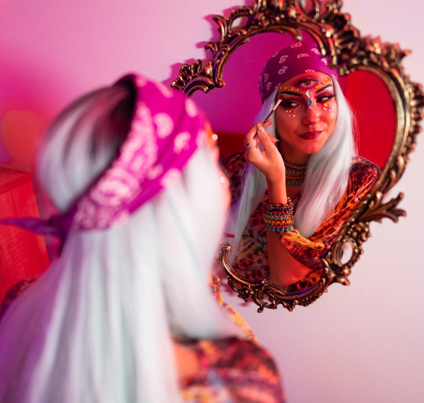 A young woman puts on makeup before taking a picture that would go well with Halloween 2021 Instagra...