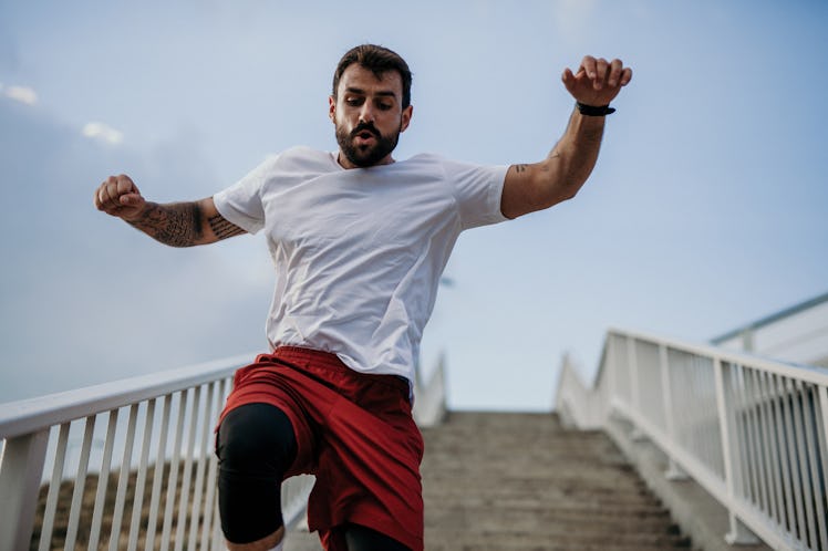 Low angle view of a Sports caucasian male person running down the stairs while hitting a street park...