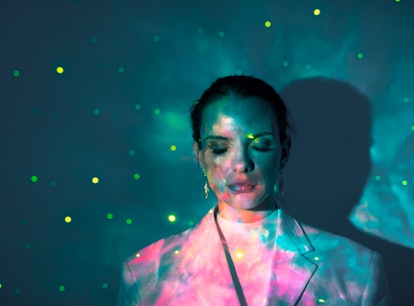 Young woman closing her eyes in glowing lights during the September 2021 new moon in Virgo, which af...