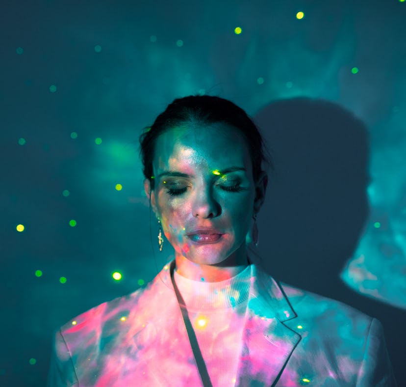 Young woman closing her eyes in glowing lights during the September 2021 new moon in Virgo, which af...