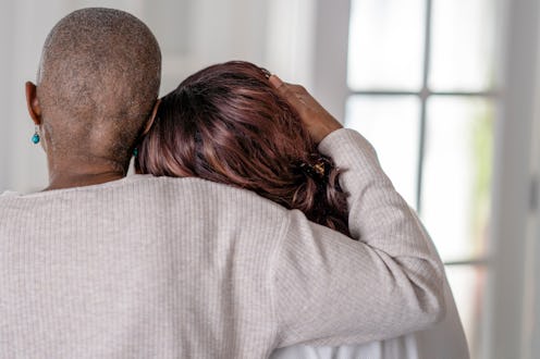 A woman who has lost her hair holds her arm around her daughter as an act of love.
