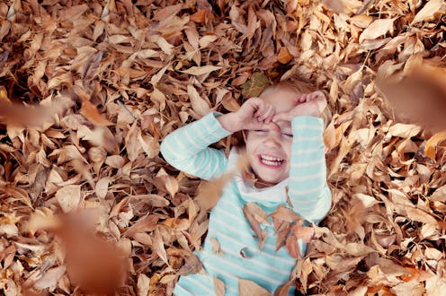kid playing in a pile of leaves