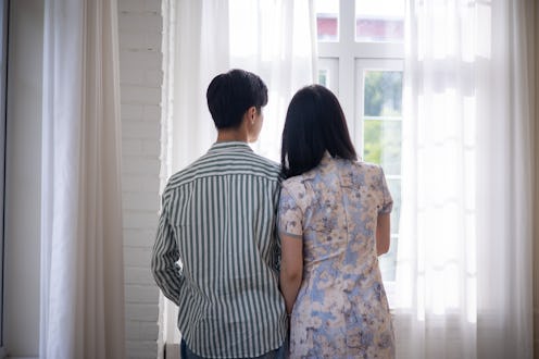 Young asian couple looking through window