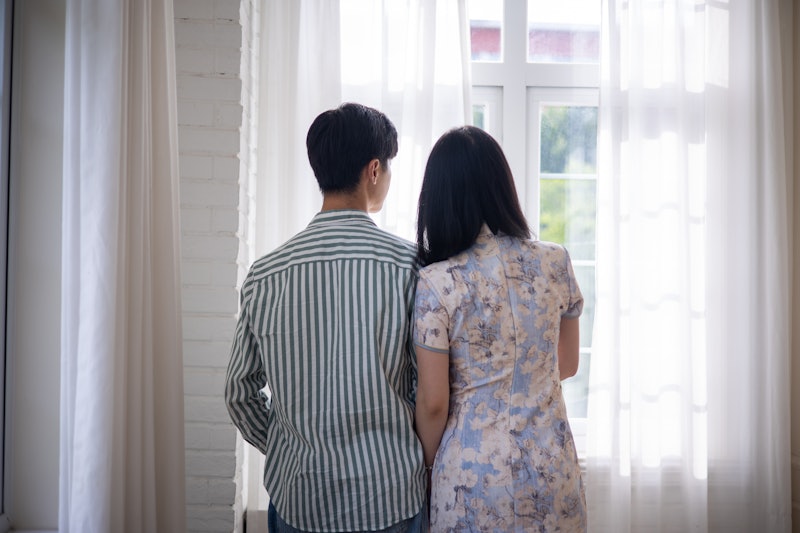 Young asian couple looking through window