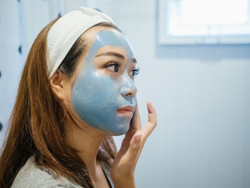 Asian woman in bathroom with facial mask, Home spa and skin care concept.