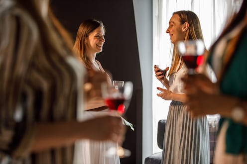 Selective focus shot of small group of female friends casually chatting and hanging out together whi...