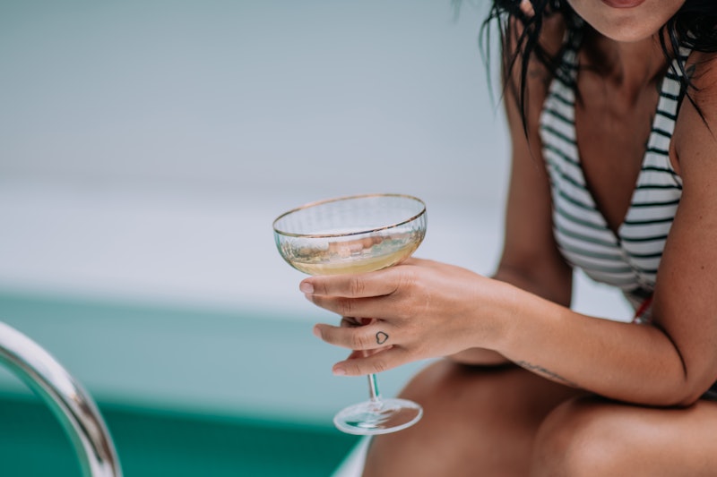 woman drinking a cocktail by the pool