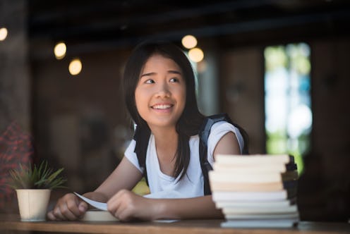 Young woman reading book sitting indoor in urban cafe.