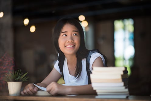 Young woman reading book sitting indoor in urban cafe.