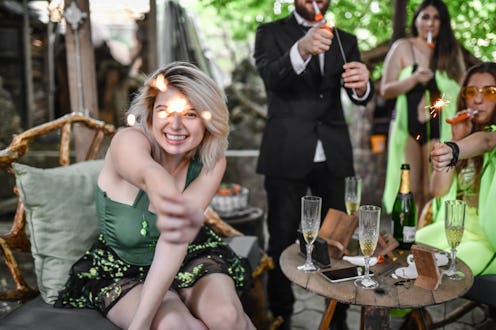 Smiling Females And Male Friend Playing With Sparklers And Confetti During Halloween Party