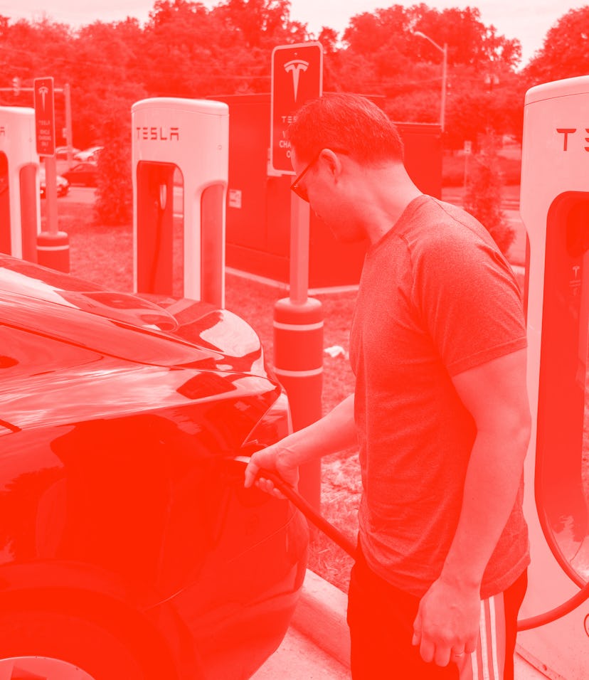 A man charges his car at a Tesla super charging station in Arlington, Virginia on August 13, 2021. -...