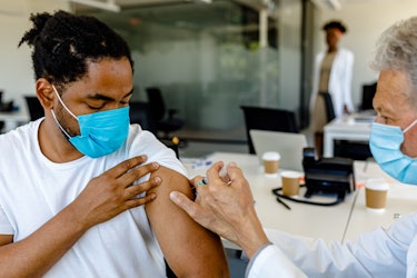 Portrait of an African-American Receiving a COVID-19 Vaccine From a Doctor at his Office.