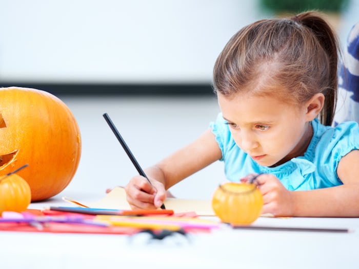 little girl coloring halloween picture with pumpkin