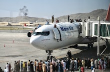 TOPSHOT - Afghan people climb atop a plane as they wait at the Kabul airport in Kabul on August 16, ...
