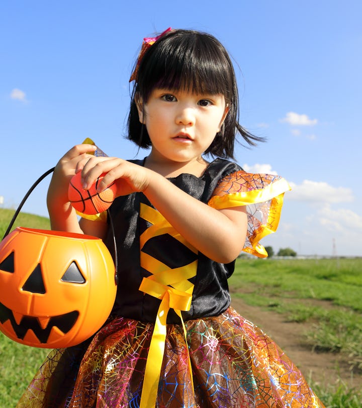 little girl dressed up in halloween costume standing outside