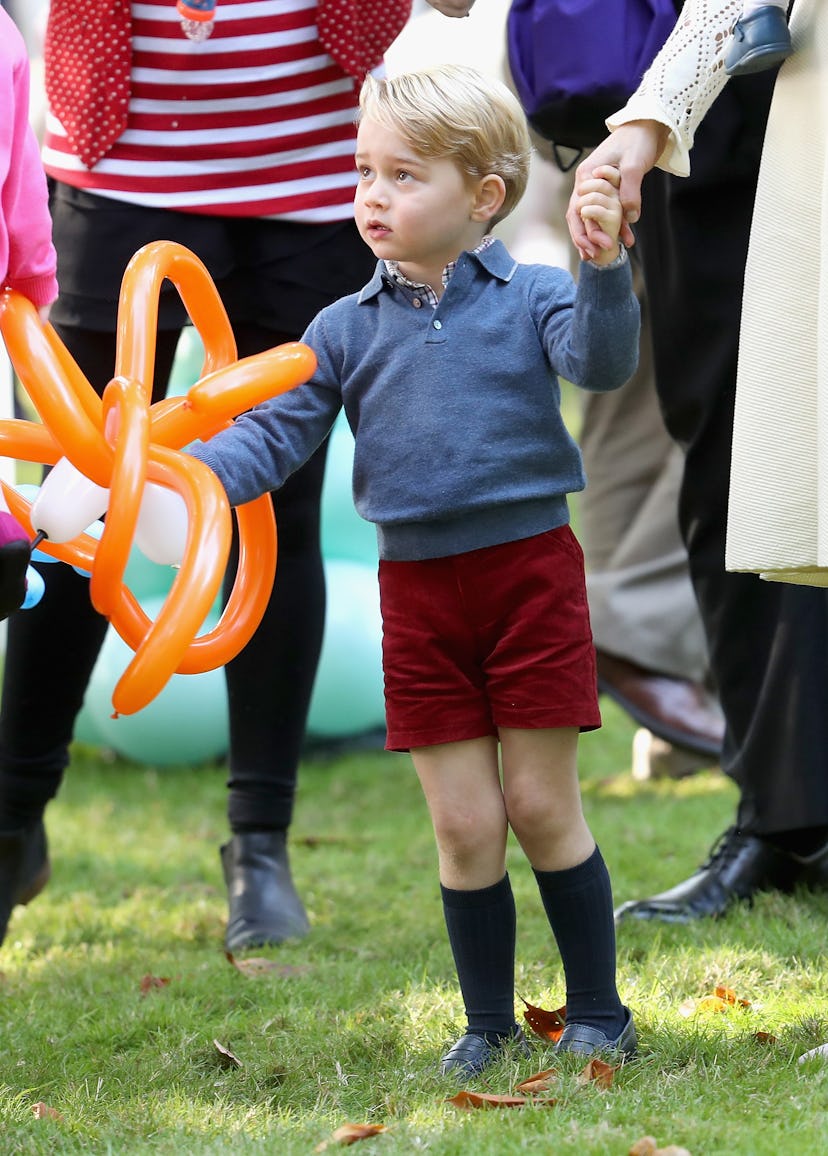 Prince George regally accepts a balloon animal.