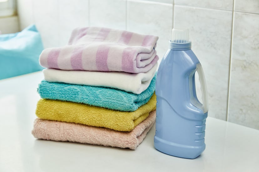 Stack of soft and colorful towels on table with detergent