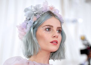Lucy Boynton wears a flower crown and pastel hair and eye makeup with small rhinestone starbursts co...