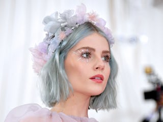 Lucy Boynton wears a flower crown and pastel hair and eye makeup with small rhinestone starbursts co...