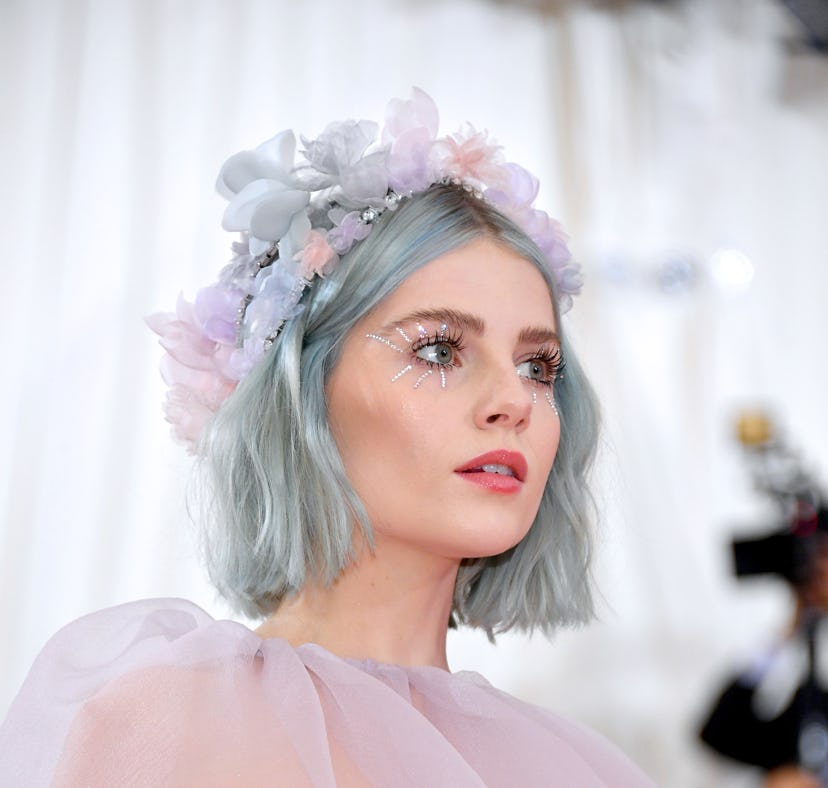 Lucy Boynton wears a flower crown and pastel hair and eye makeup with small rhinestone starbursts co...