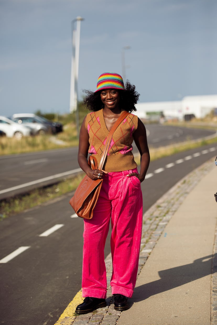 COPENHAGEN, DENMARK - AUGUST 12: Guest wearing pink pants, brown and pink knitted top and colorful r...