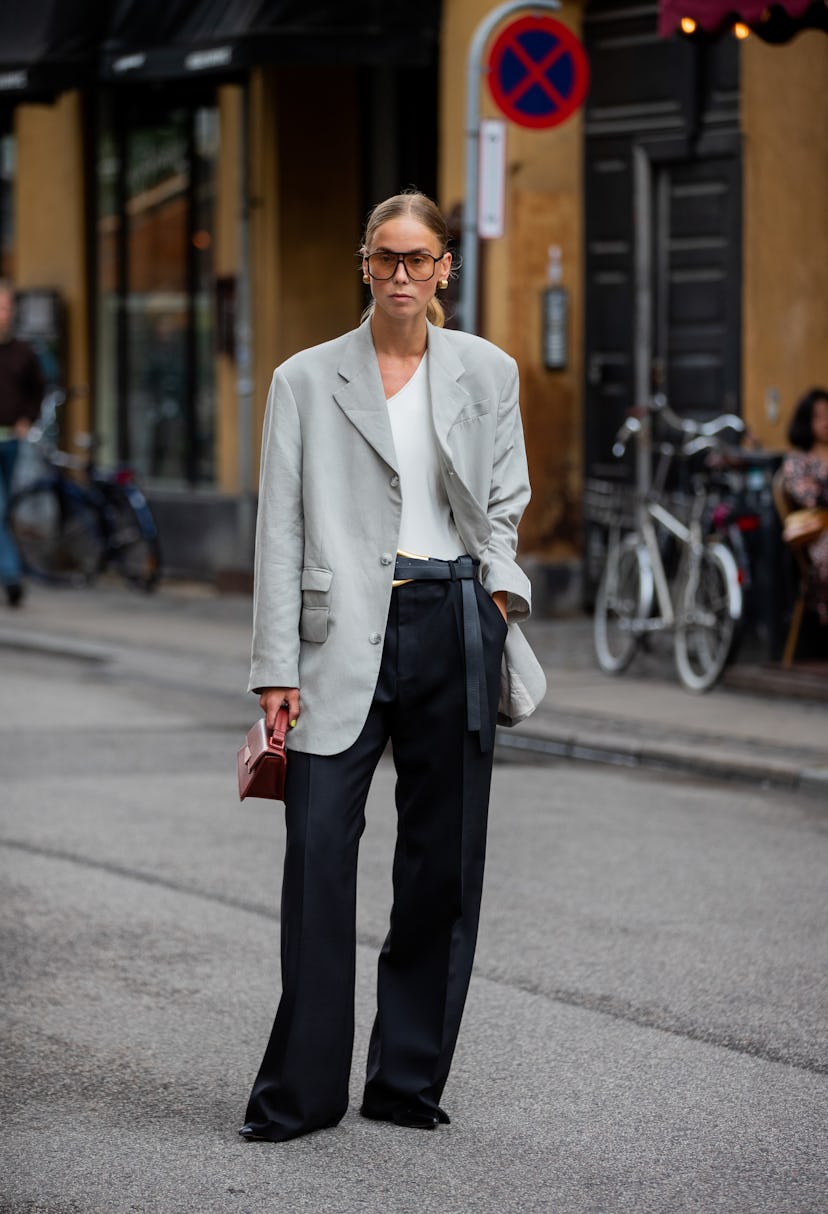 COPENHAGEN, DENMARK - AUGUST 09: A guest is seen wearing grey blazer, black pants, Acne bag, sunglas...