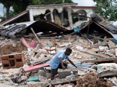 A man searches in the debris of a collapsed house after an earthquake, in Les Cayes, Haiti, on Aug. ...