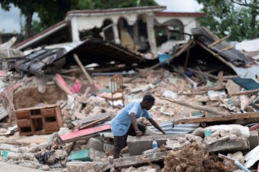 A man searches in the debris of a collapsed house after an earthquake, in Les Cayes, Haiti, on Aug. ...