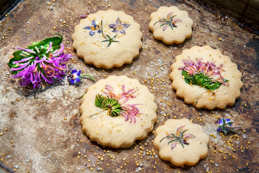 Image of shortbread cookies with edible flowers and gold sugar on top.