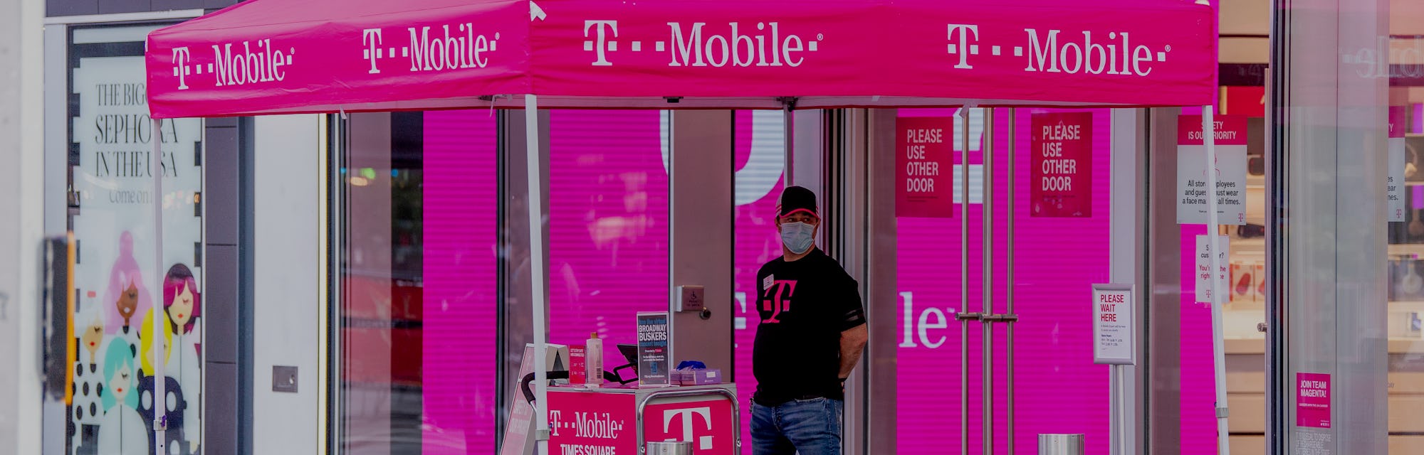 NEW YORK, NEW YORK - AUGUST 18: A clerk at the T-Mobile store in Times Square provides curb side ser...