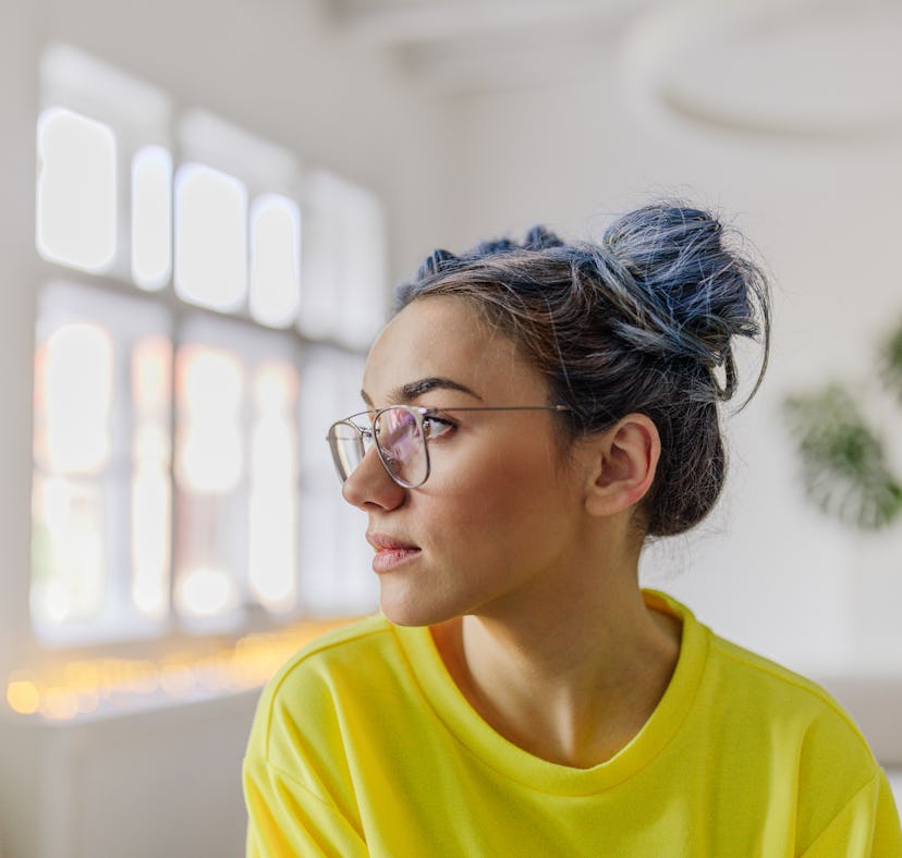 Young woman looking out the window because she's a water sign, the most nostalgic in the zodiac.
