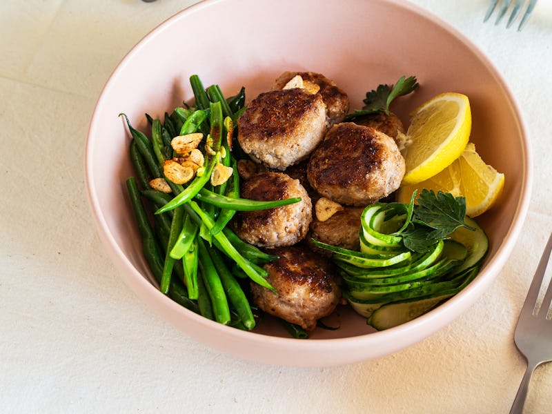 Rustic table with meal. Pork meatballs with sauteed green beans, cucumber salad, high angle view