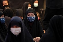 An Afghan refugee woman wearing a protective face mask looks on while attending a hussainiyah during...