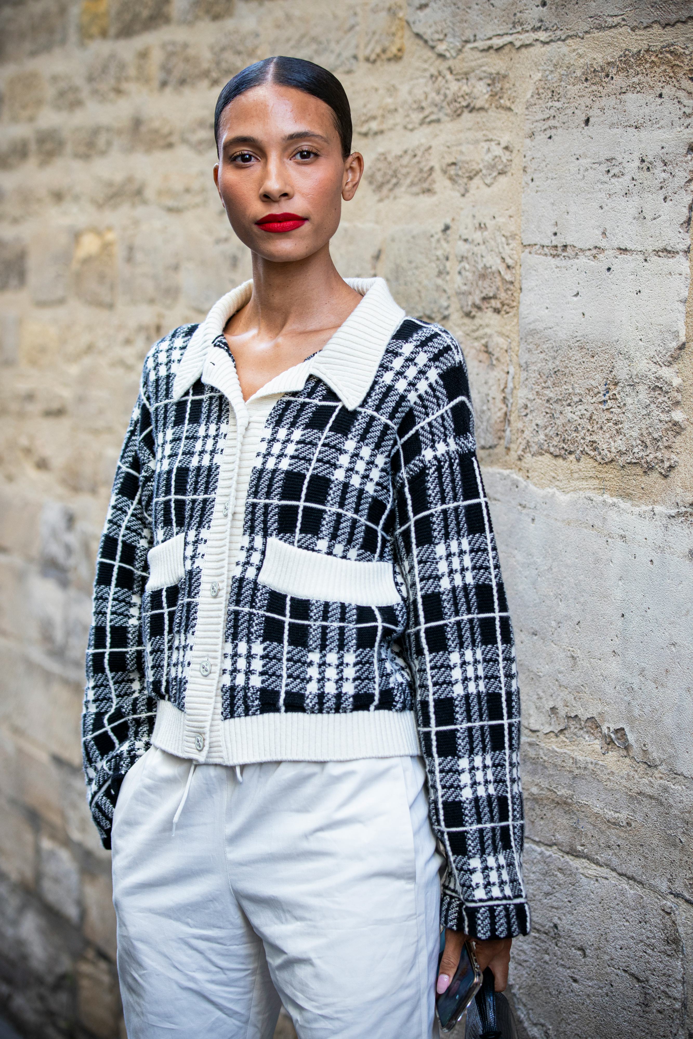 PARIS, FRANCE - SEPTEMBER 30: A guest, wearing a black and white checked cardigan and white pants, i...