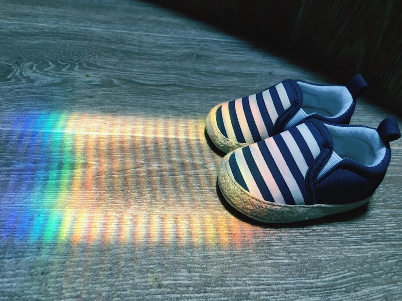 photo of baby shoes next to rainbow reflection on the ground rainbow baby announcement ideas