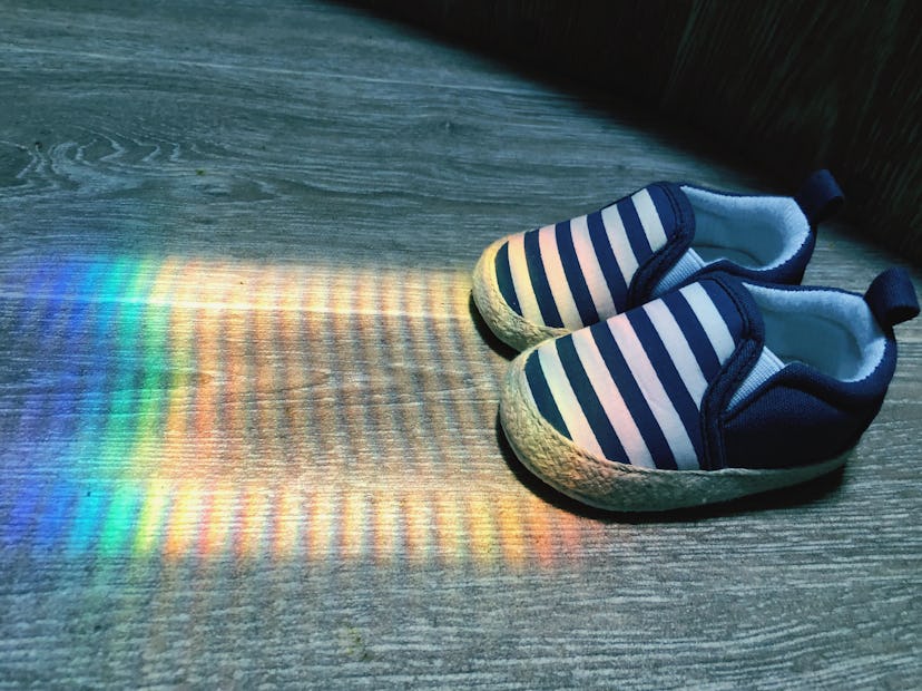 photo of baby shoes next to rainbow reflection on the ground rainbow baby announcement ideas