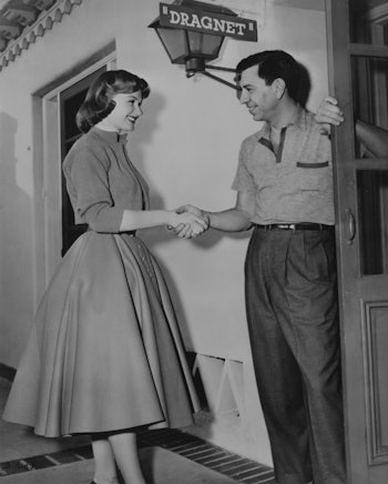 American actor Jack Webb (1920 - 1982) welcomes actress Ann Robinson onto the set of the film 'Dragn...