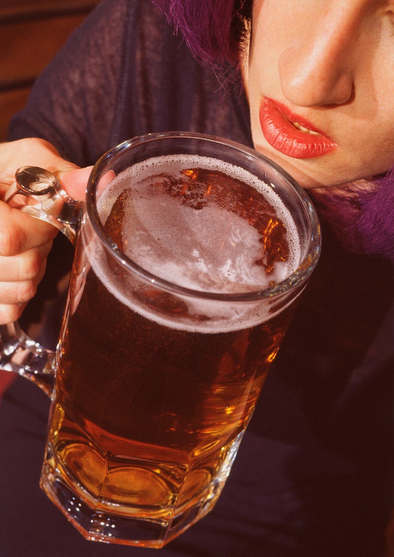 A woman drinks a massive beer alone at a bar. Going to bars alone can be an exercise in self-affirma...