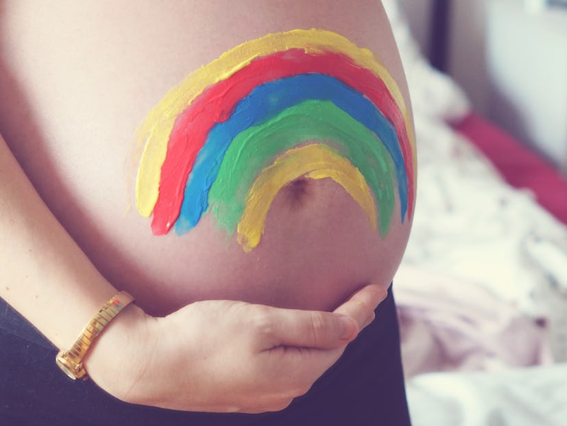 Pregnancy shot showing a rainbow painted on a baby bump as an idea for a rainbow baby announcement 