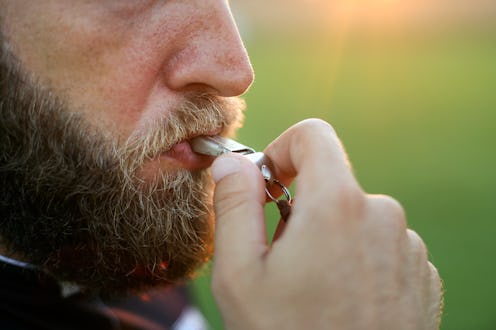 Soccer referee blowing a whistle on a field. Unrecognizable Caucasian male.