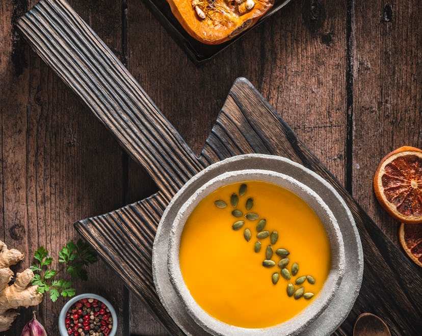 butternut squash soup topped with pumpkin seeds in a bowl on wooden table