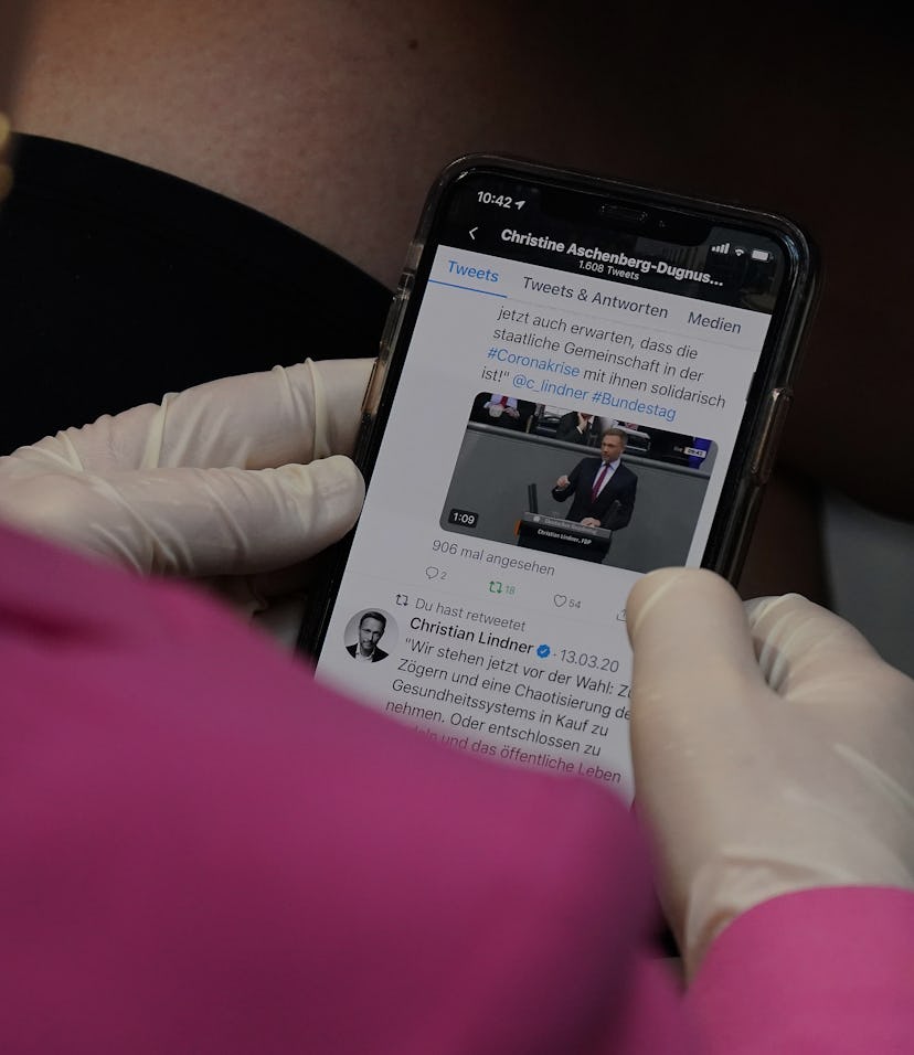 BERLIN, GERMANY - MARCH 25: A member of the Bundestag wears protective gloves as she follows a Twitt...