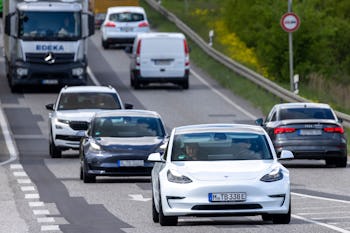 Tesla CEO Elon Musk (C-L) is seen using his mobile device as he sits in the car arriving to the cons...