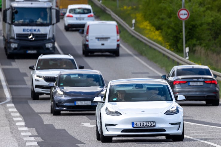 Tesla CEO Elon Musk (C-L) is seen using his mobile device as he sits in the car arriving to the cons...