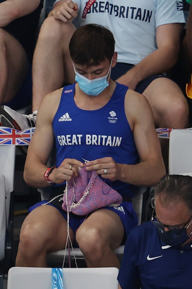 TOKYO, JAPAN - AUGUST 01: Tom Daley of Great Britain knits as he watches the Women's 3m Springboard ...