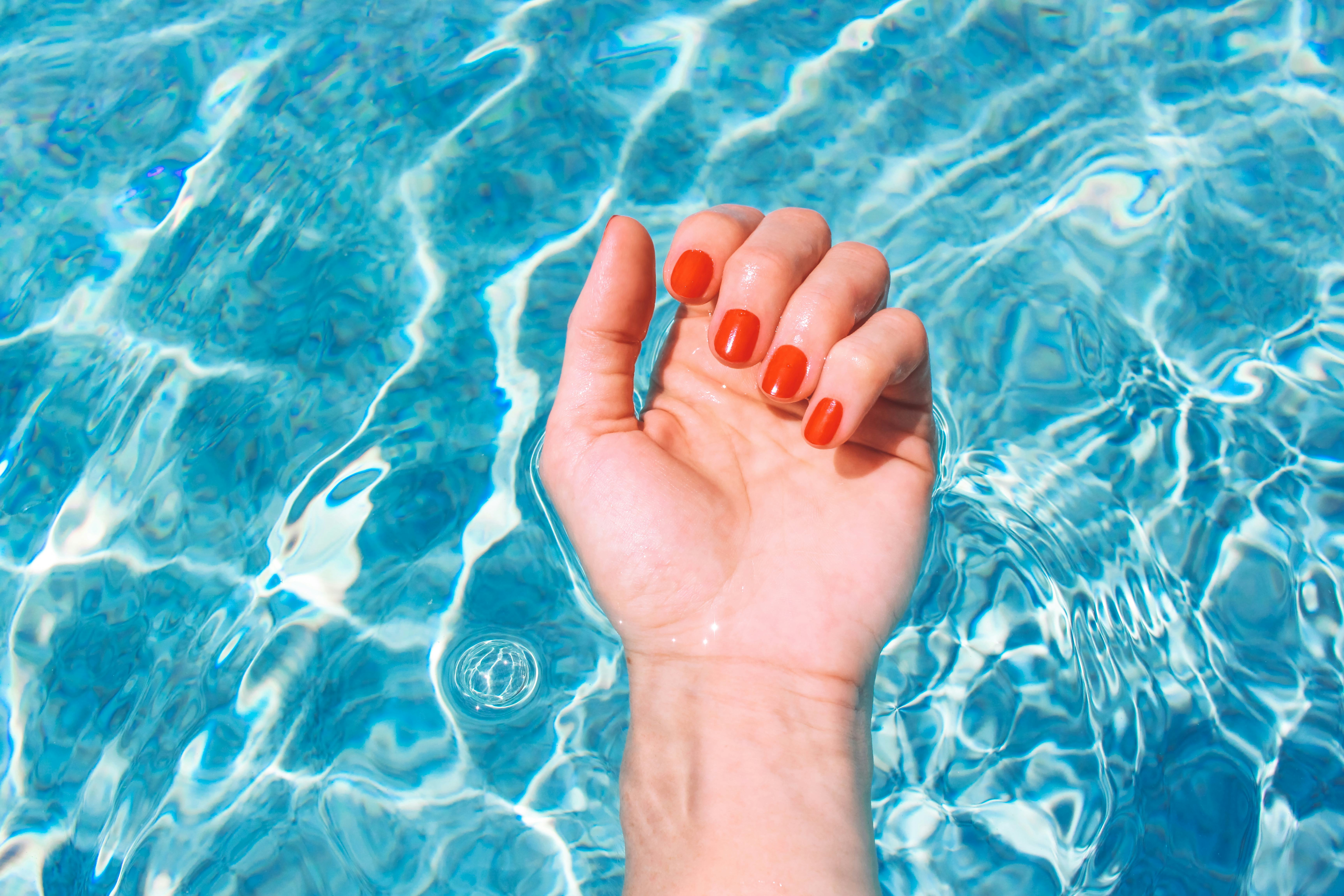 Personal perspective of a woman's wrist and palm of hand in swimming pool during a summer vacation. ...