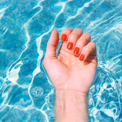 Personal perspective of a woman's wrist and palm of hand in swimming pool during a summer vacation. ...