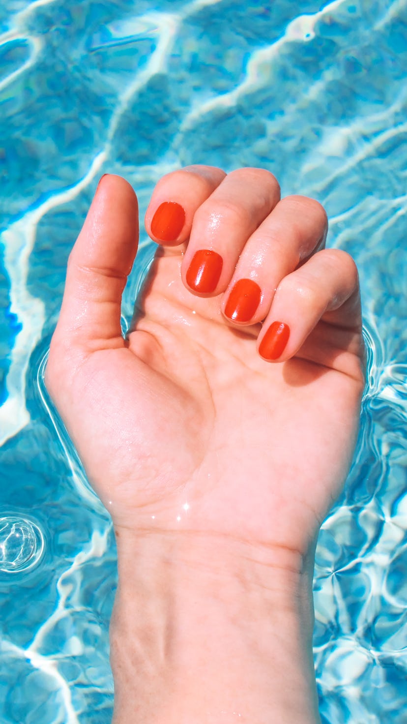 Personal perspective of a woman's wrist and palm of hand in swimming pool during a summer vacation. ...