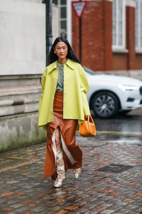 LONDON, ENGLAND - FEBRUARY 15: Fashion blogger Pornwika wears a yellow oversized jacket, an orange b...