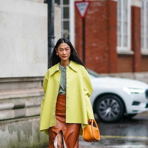 LONDON, ENGLAND - FEBRUARY 15: Fashion blogger Pornwika wears a yellow oversized jacket, an orange b...